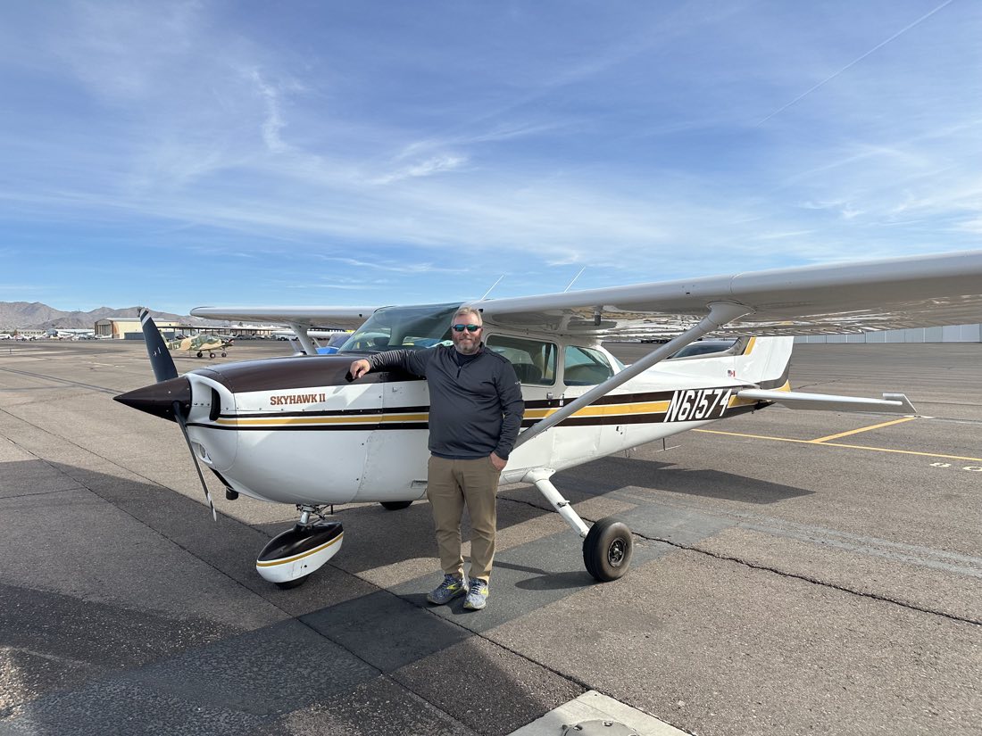 N61574 on the ramp at Falcon Field with a pilot standing beside it