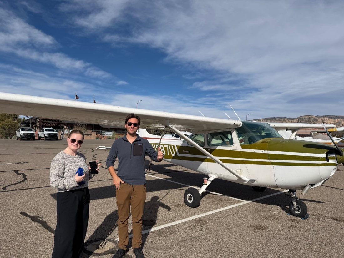 Two students beside N1287U on the ramp at Sedona, red rock cliffs behind